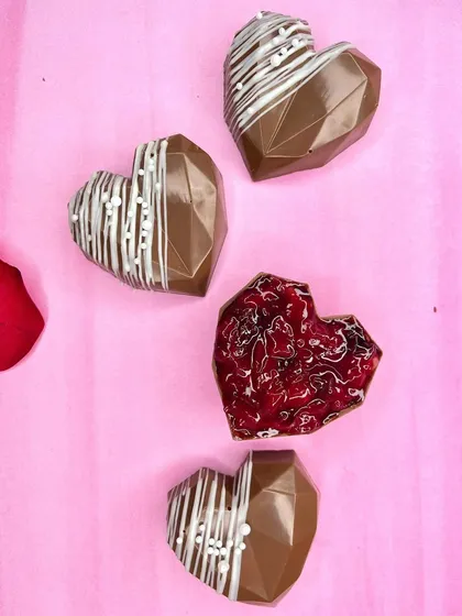 Love is sweet, and our heart-shaped chocolates make it even sweeter. These geometric chocolate hearts, some filled with jam and others drizzled with white chocolate, are perfect for celebrating Valentine's Day, anniversaries, or just because.