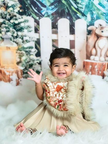 A big, happy wave from this little one during her Christmas photoshoot. The festive 'Winter Wonderland' theme brings out the joy and magic of the season.