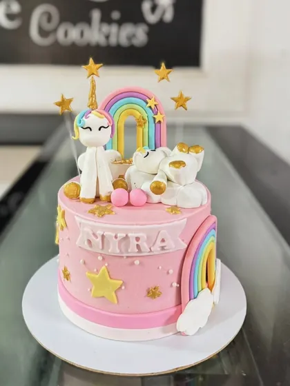 A magical unicorn and rainbow cake for Niyra. This pink cake is decorated with a fondant unicorn, rainbows, stars, and sleeping bears on clouds.