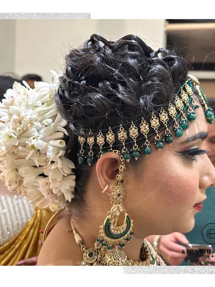 An intricate bridal hairstyle featuring a beautiful floral bun and a traditional matha patti. This is a classic and elegant choice for a bride.