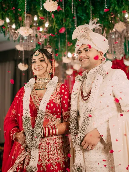 A shower of rose petals blesses the happy couple after their Varmala exchange. This shot is full of joy, color, and celebration.