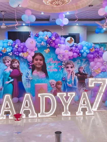 A large-scale Frozen theme for a 7th birthday, featuring a wide backdrop with multiple characters and a full balloon garland across the top.