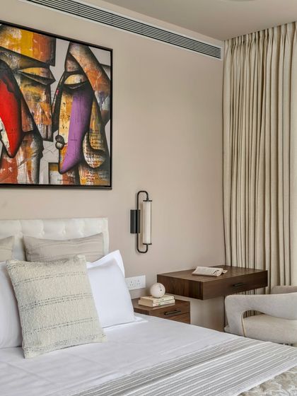 In the Parishram residence, we designed this bedroom with a focus on tactile materials and art. A floating wooden desk serves as a compact workspace, while the abstract painting adds a layer of intellectual curiosity.