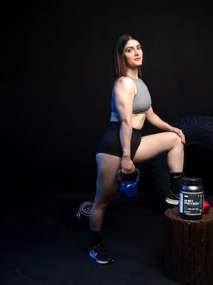This shot places the whey protein product prominently on a prop, with the model posing with a kettlebell in the background. It emphasizes the product as the central element within a fitness environment.