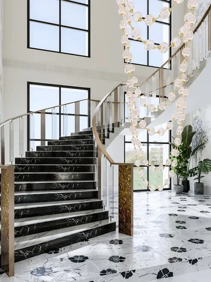 A detail shot of the sweeping black marble staircase in a grand hotel lobby, with a cascading crystal light fixture adding a touch of modern artistry.