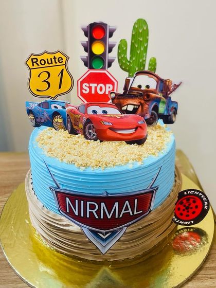 A cool racing car themed cake with a stoplight and checkered flags.