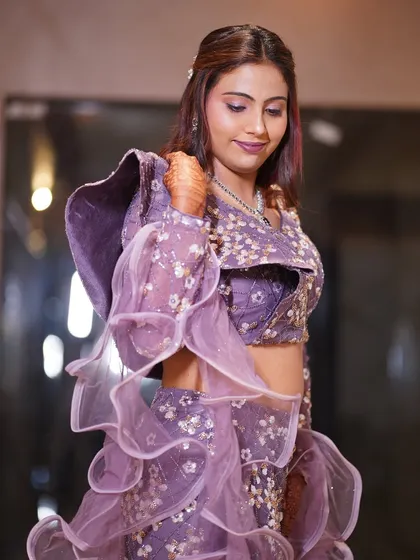 A full view of Monica's outfit and makeup. The ruffled sleeves and intricate embroidery are balanced with a sophisticated makeup and hair look.