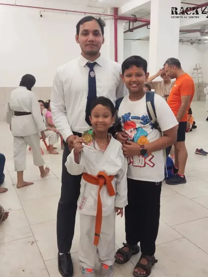 A coach stands with two of our young medalists. Moments like these highlight the strong bond between our instructors and students on their journey to success.