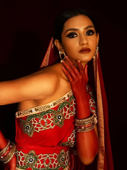 A detailed shot of the embroidered saree and the model's expressive pose. The warm, focused light creates an intimate and luxurious mood.
