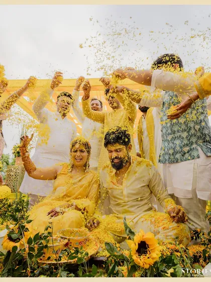 The couple and their friends celebrating with a shower of marigold petals, a perfect capture of the Haldi's joyful chaos.
