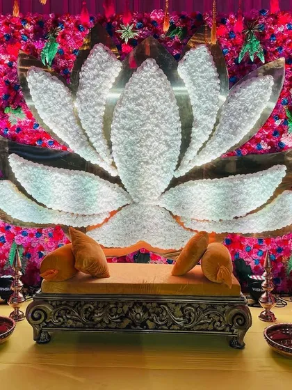 A stunning baby shower seating area with a large white lotus backdrop against a wall of vibrant pink and red flowers.