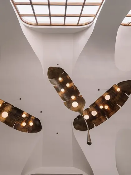 Lighting can be the jewelry of a space. In this double-height living room, we collaborated with artists to create this dramatic installation of oversized, illuminated metal fronds. The piece fills the grotto-inspired ceiling, casting a warm glow and acting as a magnificent sculptural focal point.