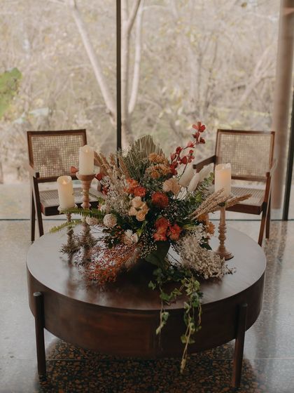 A large floral centerpiece and candles on a coffee table, set for an intimate gathering or celebration in our glass-walled lounge.