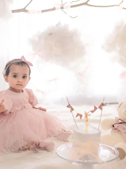 Sitting pretty with her first birthday cake and teddy bear. A classic and adorable shot to celebrate turning one.