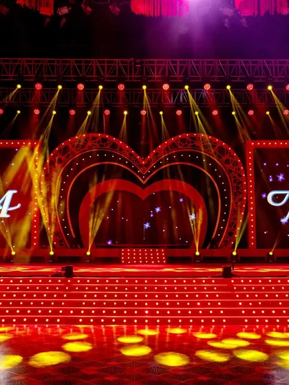 A clear, vibrant shot of the custom-designed stage, highlighting the bright lights, the couple's monogram, and the multi-level platform for performers.