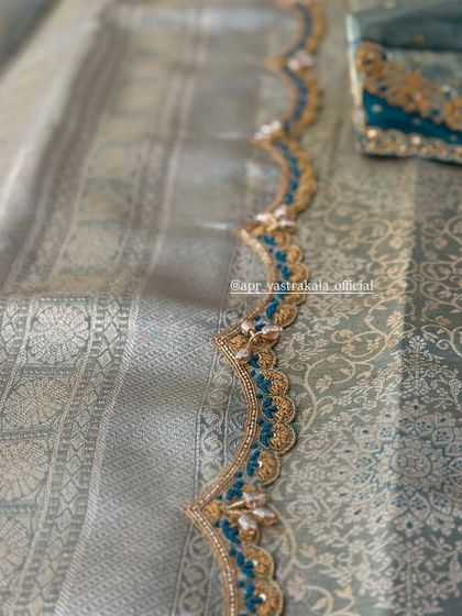 A scalloped saree border with blue and gold embroidery.