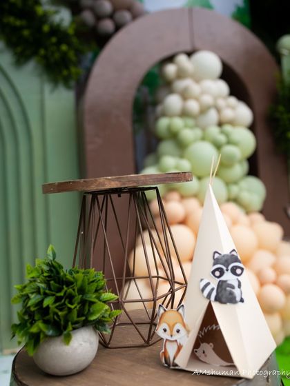 A close-up of a miniature teepee with a raccoon peeking out, one of the many playful details in Advaith's woodland party.