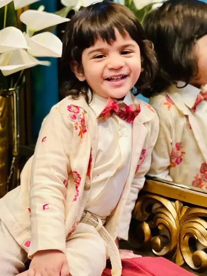 A joyful moment captured during the shoot. The reflection in the mirror shows another angle of the beautifully detailed floral embroidery on the jacket.
