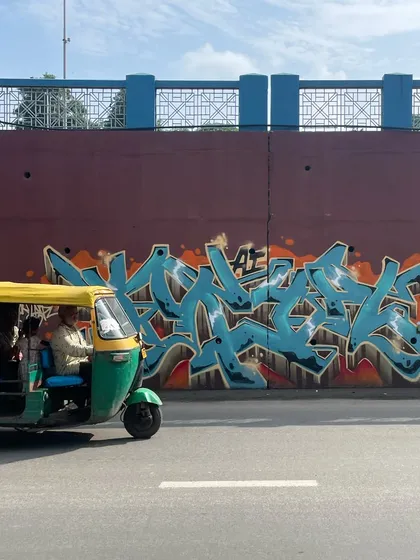 An auto-rickshaw rolling past my "KRYPT" piece in Ahmedabad. The art becomes part of the city's fabric, a backdrop to everyday life.