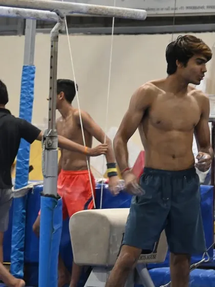 A senior gymnast takes a breather between routines, his physique a testament to his hard work.