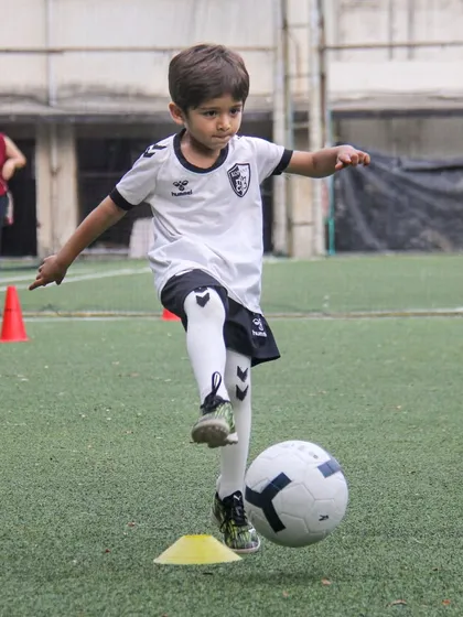A player practices a ball lift over a cone, a drill that teaches delicate touch and control for overcoming obstacles on the field.