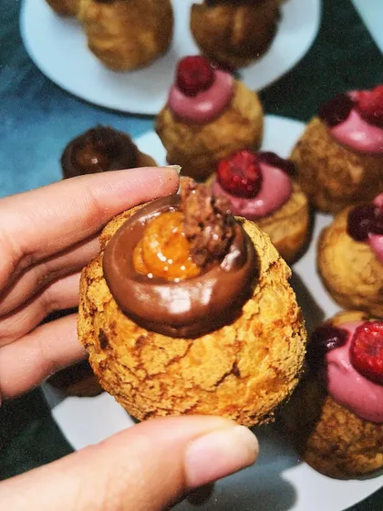 A close-up of a chocolate and caramel filled choux pastry, held up to show the delicious filling. These were part of my Father's Day specials.