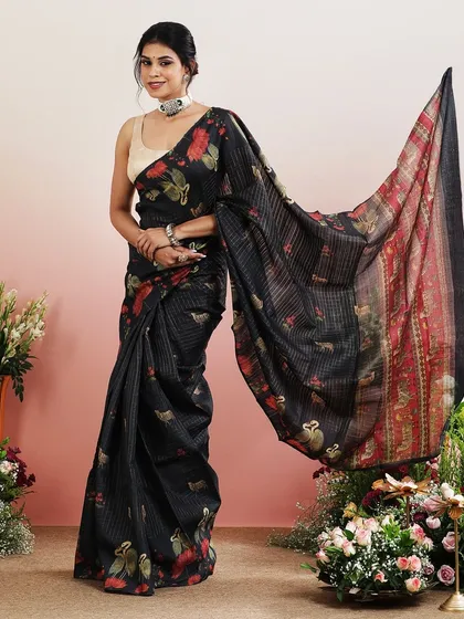 The flowing pallu of the black printed saree creates a dramatic and graceful effect.