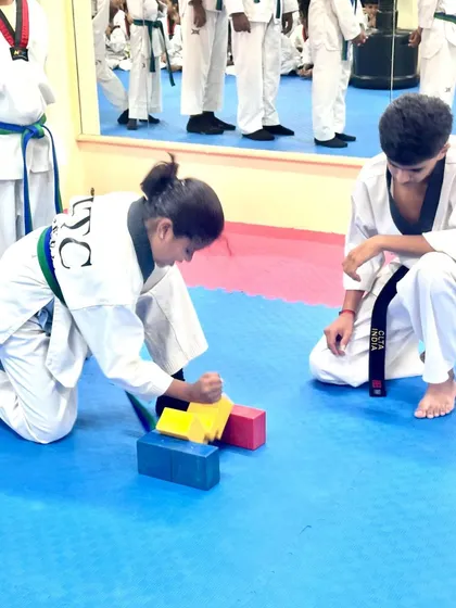 A student breaks through a stack of blocks.