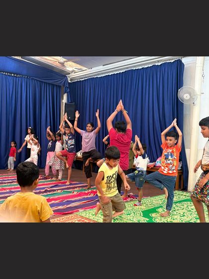 Young yogis practice the tree pose (Vrikshasana) during a kids yoga class. This pose is wonderful for improving balance and concentration in a fun, accessible way.
