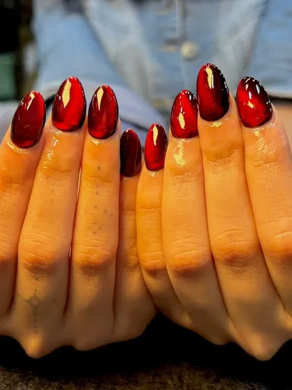 A head-on view of the stunning red cat-eye nails, showing the intense color and the mesmerizing light effect on each nail.