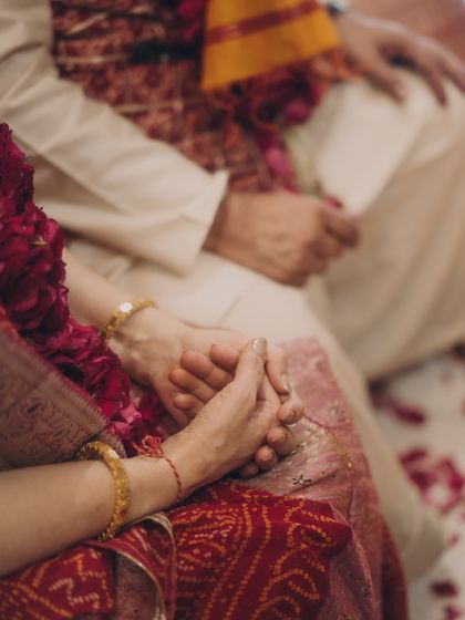 A close-up of hands clasped during a ceremony. This image is part of our 'Colour Therapy' story, where we explore how to use bold colors like red for the whole family, not just the bride.