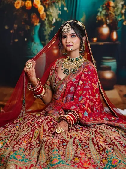 A seated pose that beautifully displays the lehenga's flare and the intricate details of the makeup and jewelry, a result of our comprehensive training.