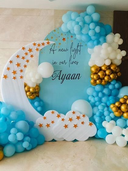 A celestial 'A new light in our lives' theme for a baby's arrival. The decor includes a moon-shaped cutout, star elements, and a beautiful arrangement of blue, white, and gold balloons.