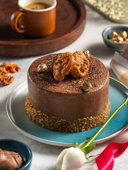 A coffee and hazelnut mini cake, styled with a cup of espresso and a white rose for an elegant and aromatic presentation.