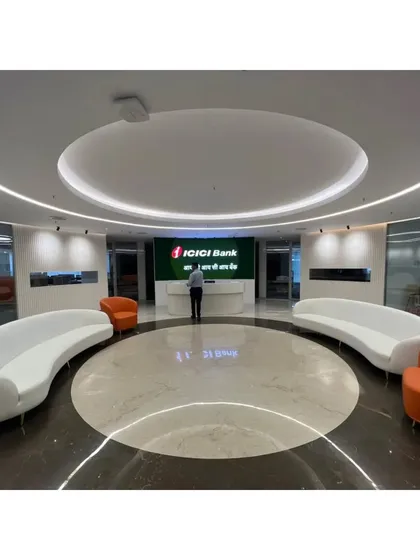 The ICICI Bank reception lobby with a person for scale, illustrating the grand proportions of the space. The circular design naturally guides visitors toward the central reception desk.