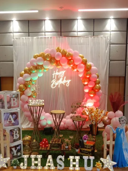 The warm lighting enhances the gold and pink balloons in this Frozen-themed birthday decoration.