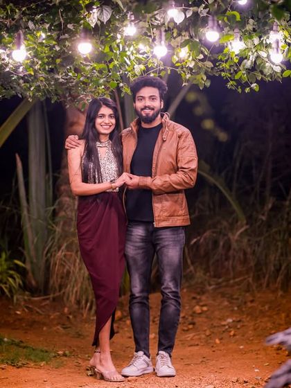 A full-length portrait of a couple under a canopy of hanging lights, showcasing the magical ambiance of our outdoor night sets.