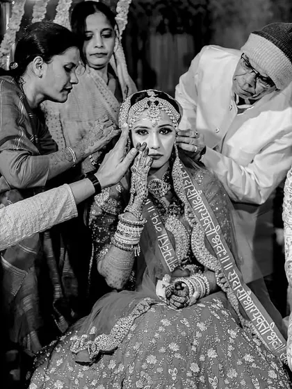 A poignant black and white moment where family members gently wipe away the bride's tears during a ceremony. A powerful image of love and support.