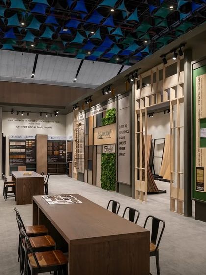 Another view of the Realply aisle, showing the extensive wall space dedicated to showcasing plywood and veneer samples. The design incorporates long tables for group discussions and product comparisons.
