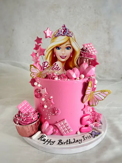 This Barbie cake is all about the pink and the sparkle. It's a tall, elegant cake decorated with edible butterflies, chocolate bars, and geometric hearts, perfect for a glamorous birthday girl.
