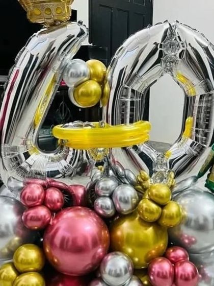 A close-up of a milestone birthday balloon bouquet. This arrangement features large silver foil number '40' balloons, surrounded by a base of pink, gold, and silver chrome balloons.