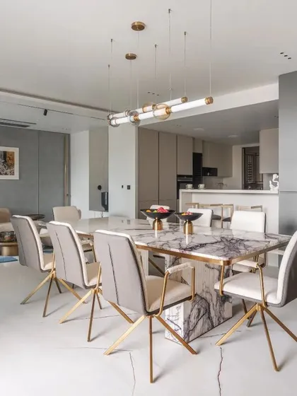 This open-plan dining and living area at Park West demonstrates a seamless transition between zones. The elegant marble dining table with brass-legged chairs is complemented by the patterned grey wall, creating a cohesive design narrative that flows through the entire space.