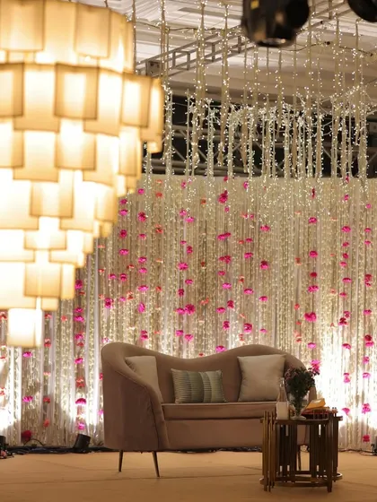 A sangeet stage that exudes opulence and romance. A cascade of white and pink floral strings, paired with a modern tiered chandelier, created a dreamy and luxurious backdrop.