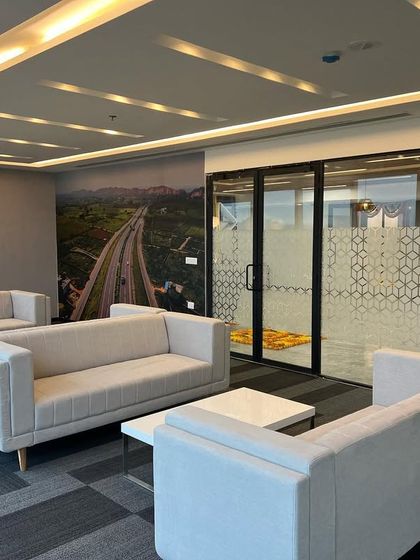 The waiting lounge at the Cube Highways office, featuring comfortable modern sofas and a wall mural depicting a highway. This branding element immediately connects the space to the company's core business.