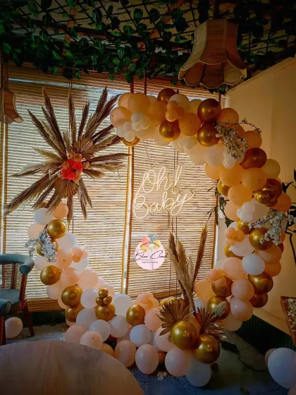 A boho-chic 'Oh Baby' shower decoration with a balloon ring in neutral tones, accented with pampas grass.