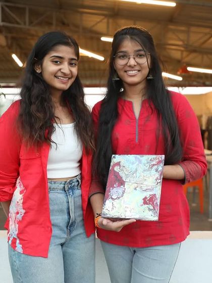 Two participants from the Setty Mech Engineers workshop, happy with their finished fluid art pieces.