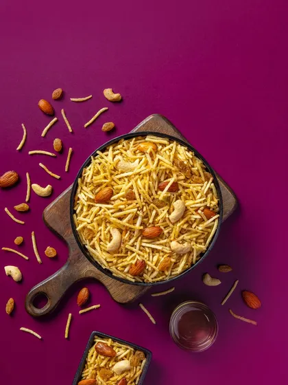 A dry fruit and potato stick mixture styled for Sartaj Sweets. The rich magenta background creates a premium feel for this packaging photography project.
