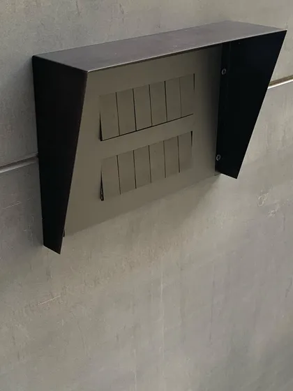 Even a switchboard can be a design element. Here, a custom metal hood protects outdoor switches, its faceted form echoing the architectural language of the home. Every detail is considered.
