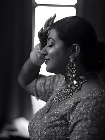 A black and white portrait of a bride in a moment of quiet reflection, her hand to her forehead.