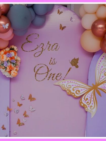 A close-up of a butterfly-themed first birthday backdrop. The soft peach and purple color palette and elegant butterfly graphics create a sophisticated look.